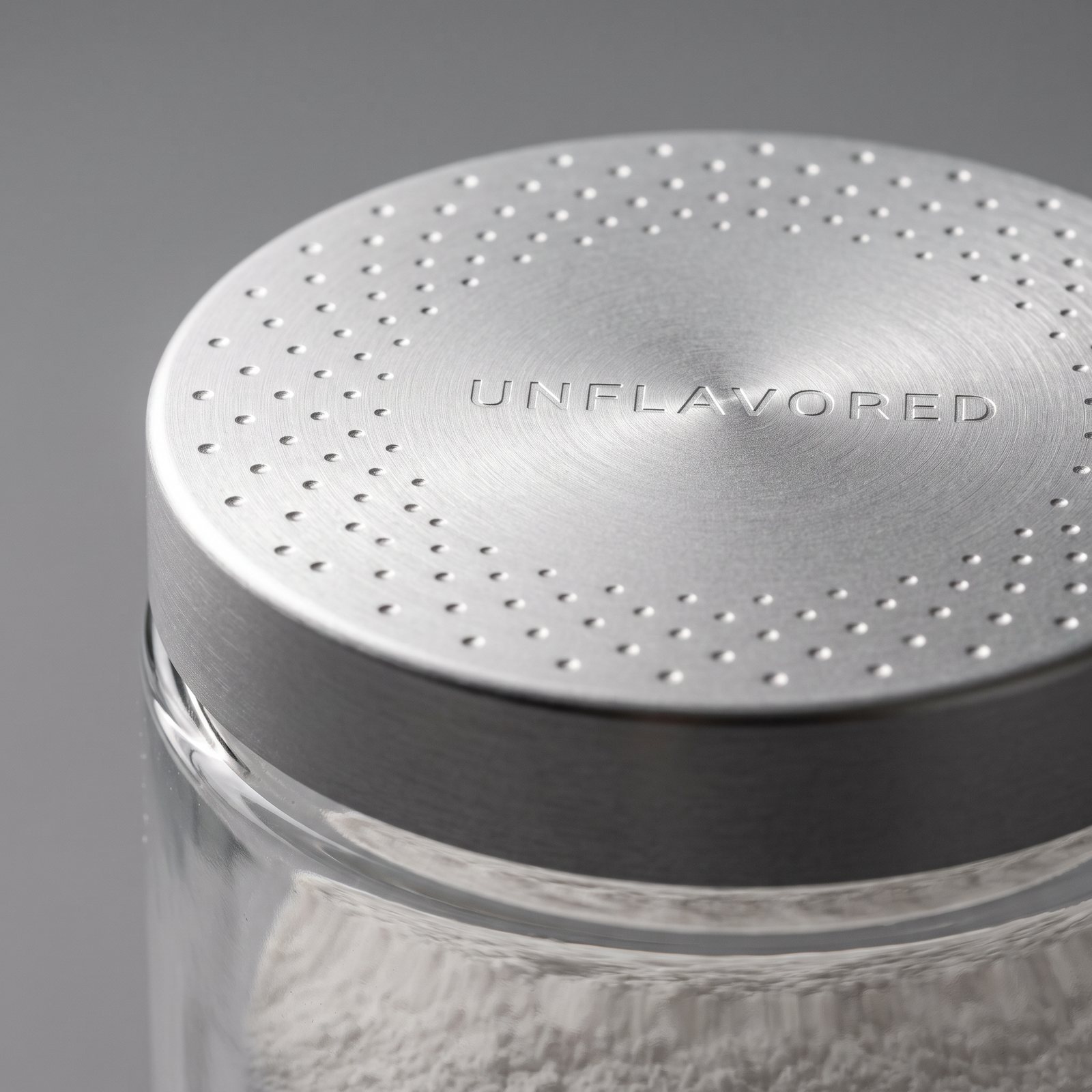 Close-up of the brushed aluminum lid, embossed with a field of dots and the word Unflavored