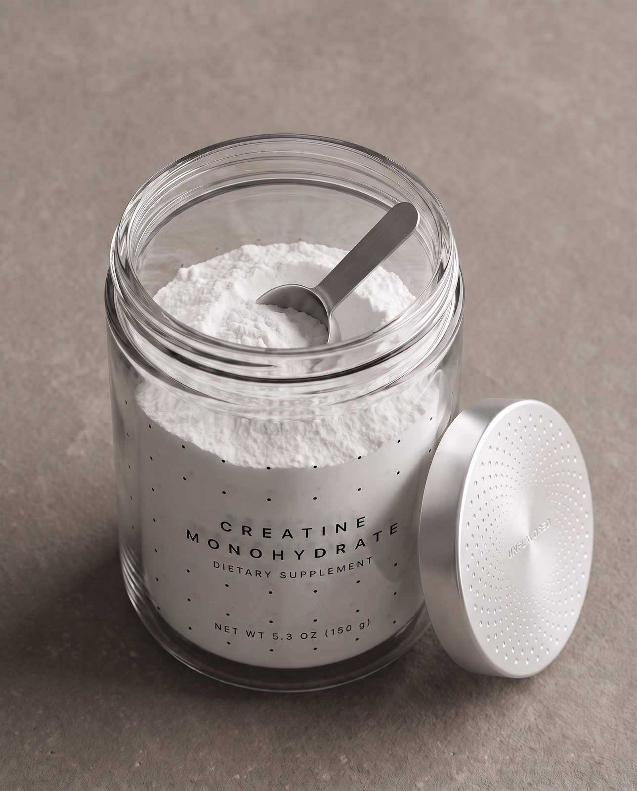 Looking down into the open jar: white creatine powder with a steel scoop, the thick double glass rim visible